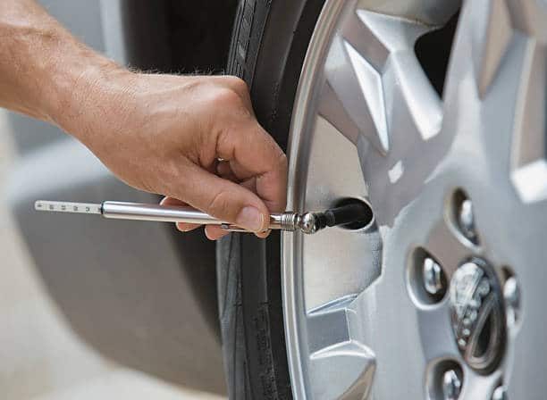 Garagiste qui contrôle la pression des pneus d'une voiture